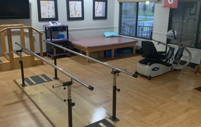 A physical therapy room equipped with parallel bars and exercise equipment.
