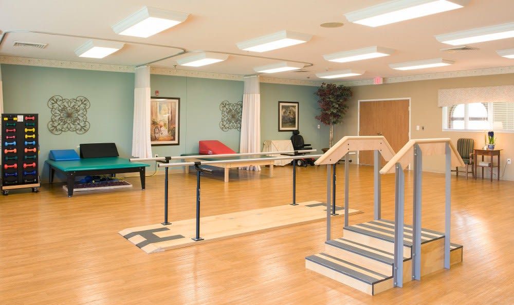 A bright and spacious rehabilitation therapy room equipped with parallel bars for physical therapy exercises.