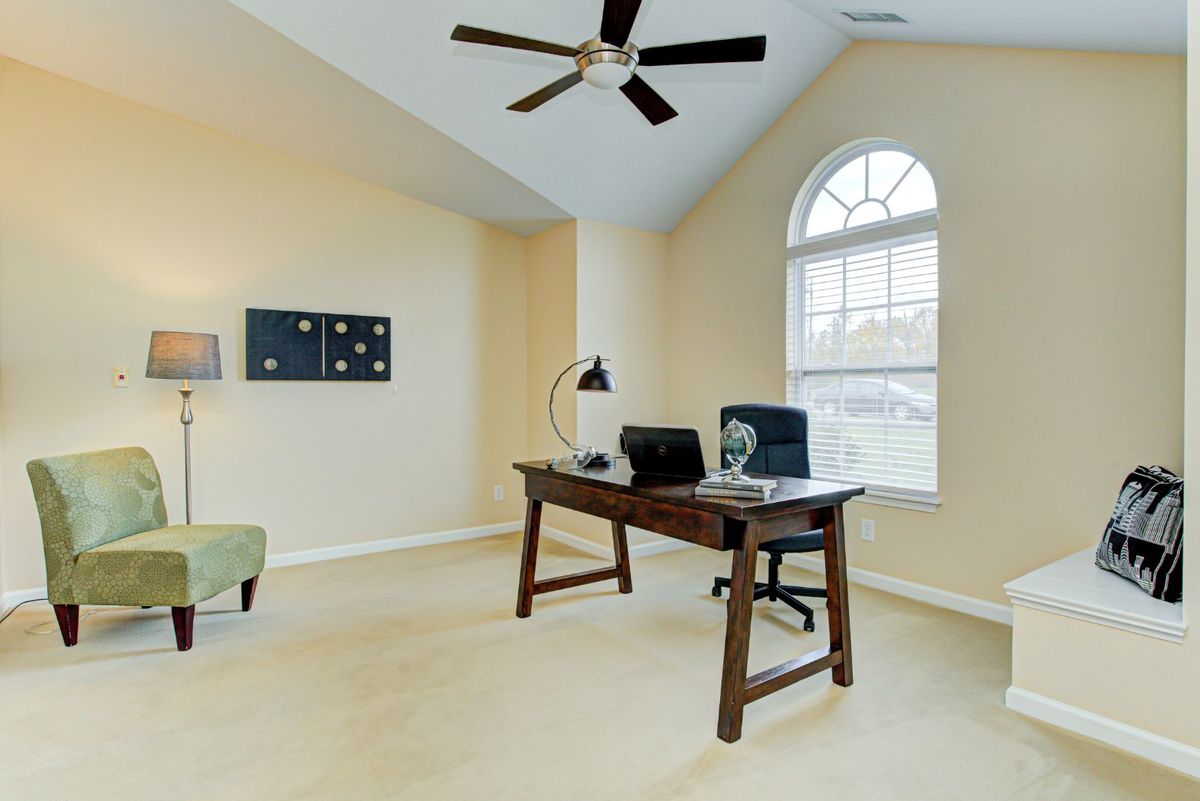 A bright and spacious home office with a large desk and window.