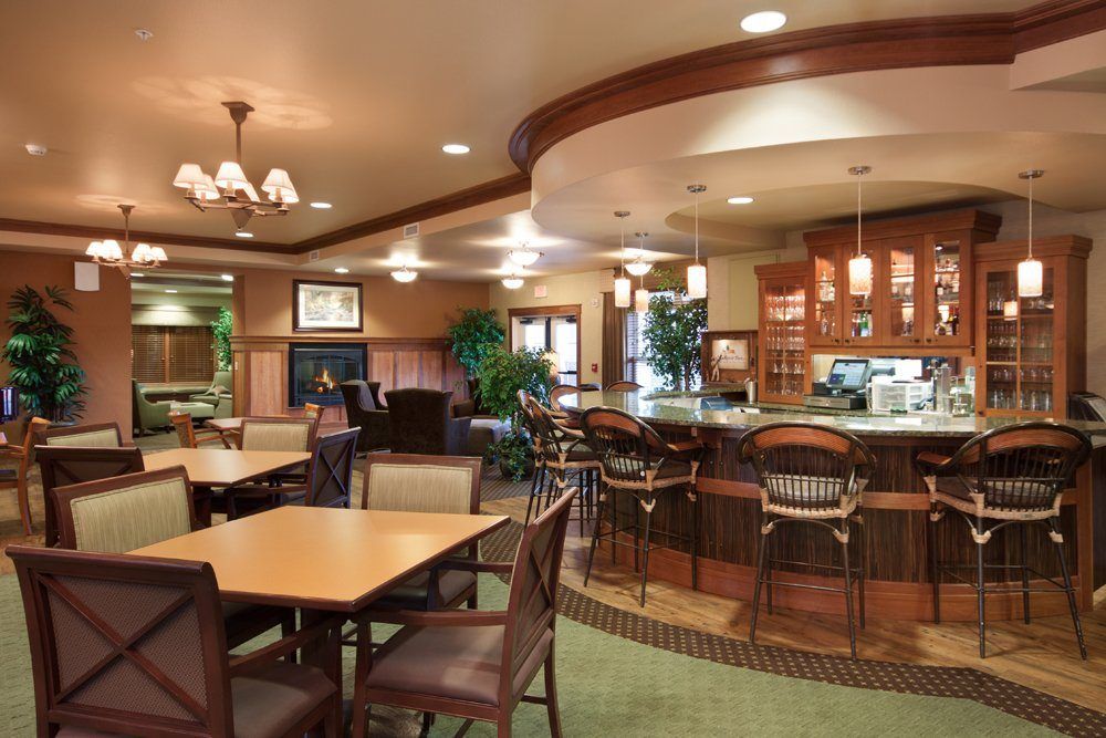 A cozy restaurant interior with a bar counter, tables, and chairs.