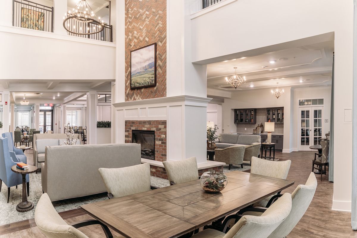 A luxurious open-plan living and dining area featuring a modern design with elegant furnishings, a fireplace, and a chandelier.