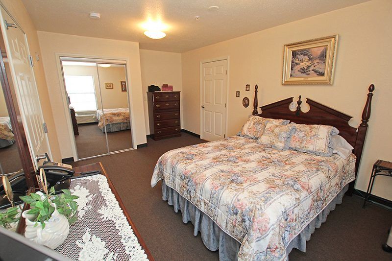 A cozy bedroom with a neatly made bed, wooden furniture, and decorative elements.