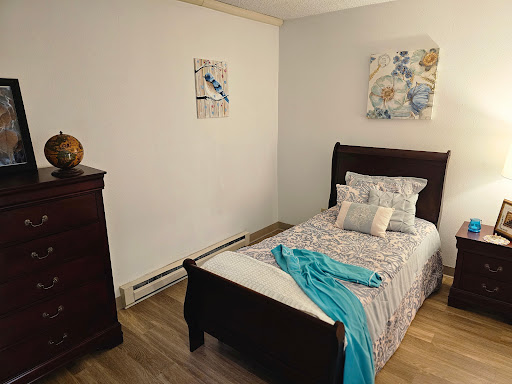 A cozy and well-decorated bedroom featuring a single bed with light-colored linens and decorative pillows.