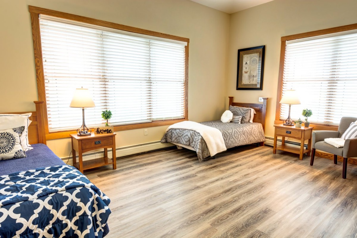 A cozy bedroom with twin beds, wood flooring, and soft lighting from table lamps.