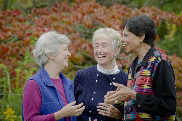 Three women enjoying a conversation outdoors in the fall.