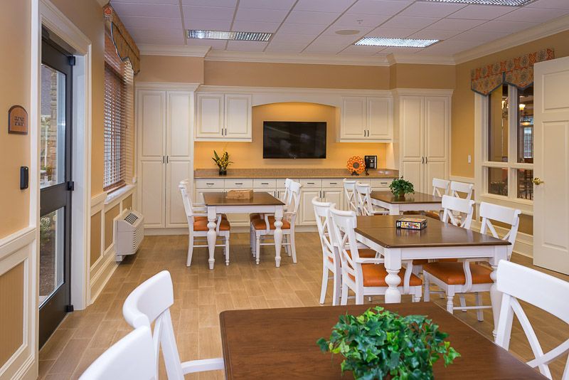 A modern and cozy kitchen and dining area with neatly arranged tables and chairs, complemented by decorative plants.