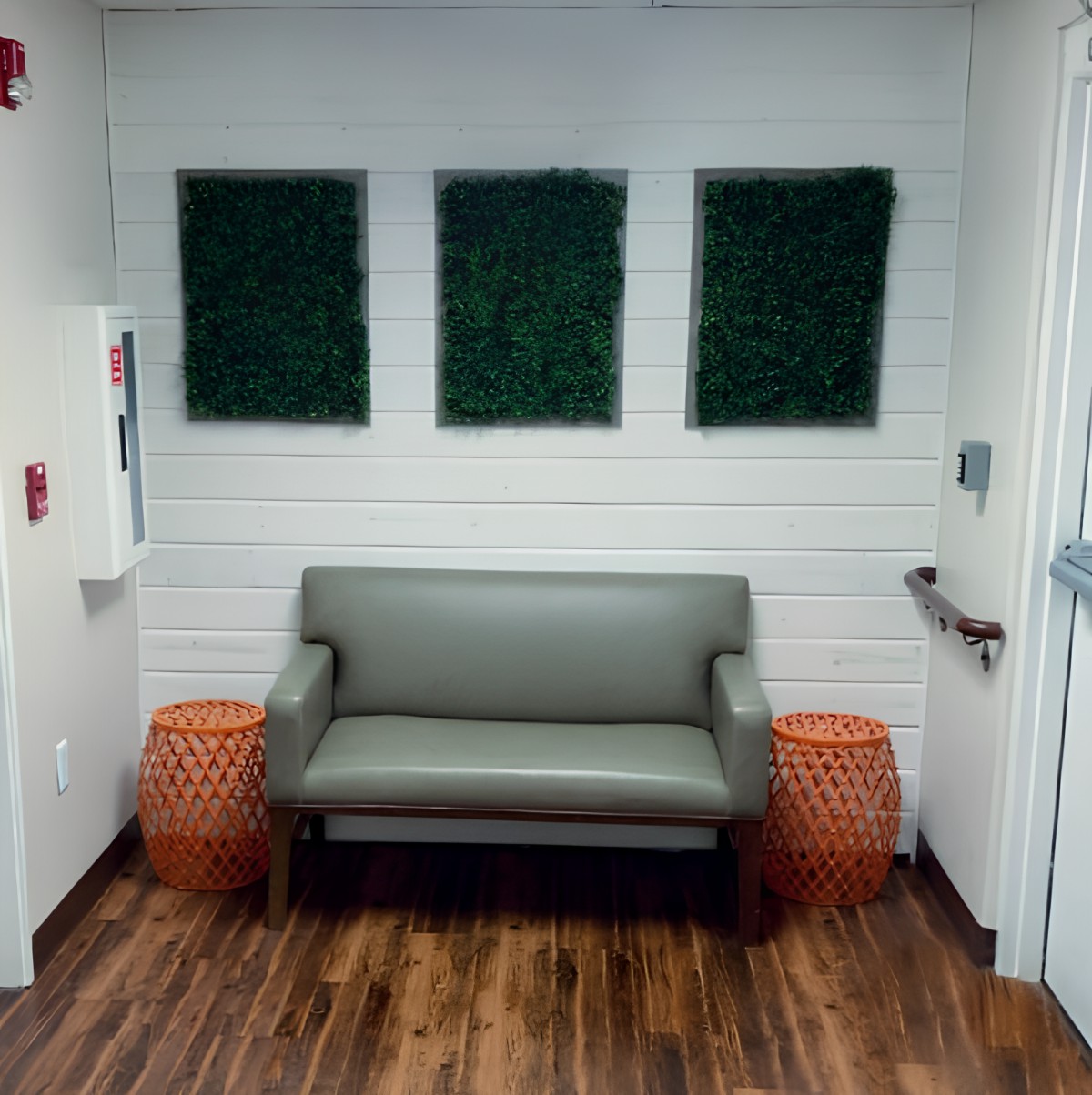 A modern waiting area with a sofa and plant decor on the wall.