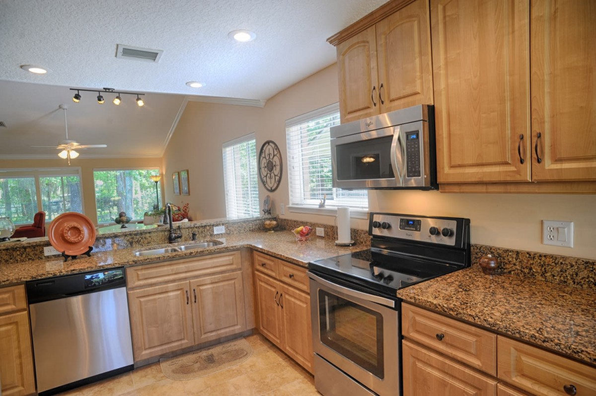 A modern kitchen with wood cabinets, stainless steel appliances, and granite countertops.