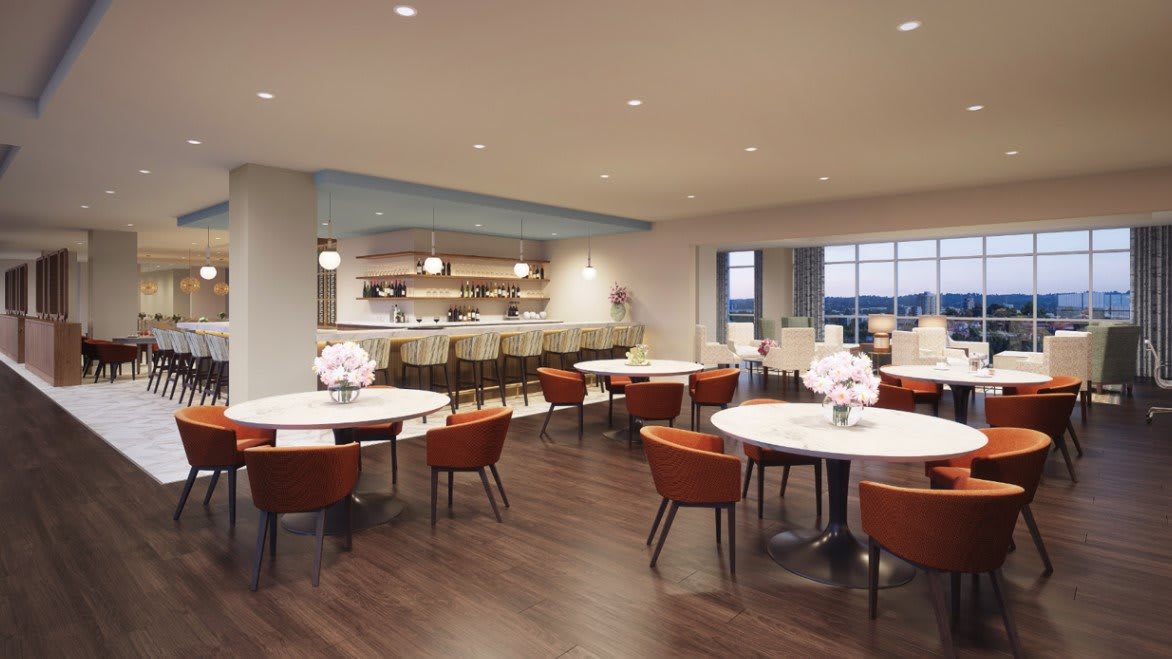 A modern dining area with round tables and a bar counter, featuring elegant seating arrangements and soft lighting.