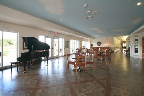 A spacious dining area with a grand piano and several tables and chairs.