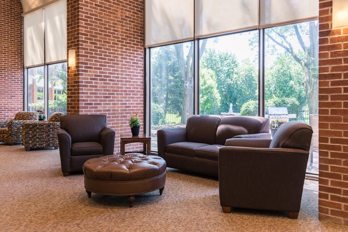 A cozy lounge area with leather furniture and large windows letting in natural light.