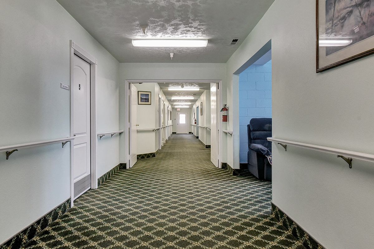 An empty hallway with patterned carpet and several doors along the sides.