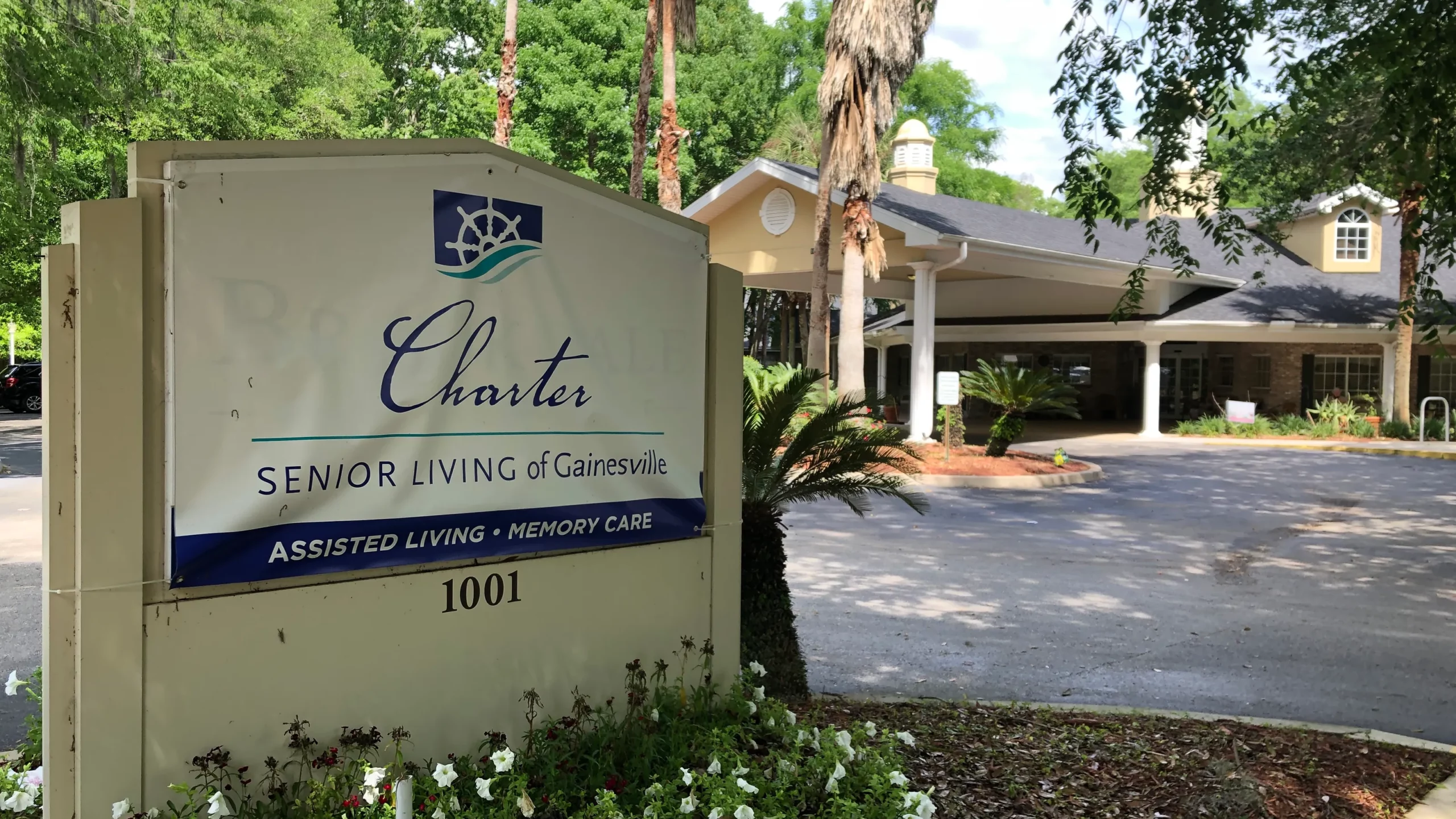 Entrance sign for a senior living community surrounded by trees and landscaping.