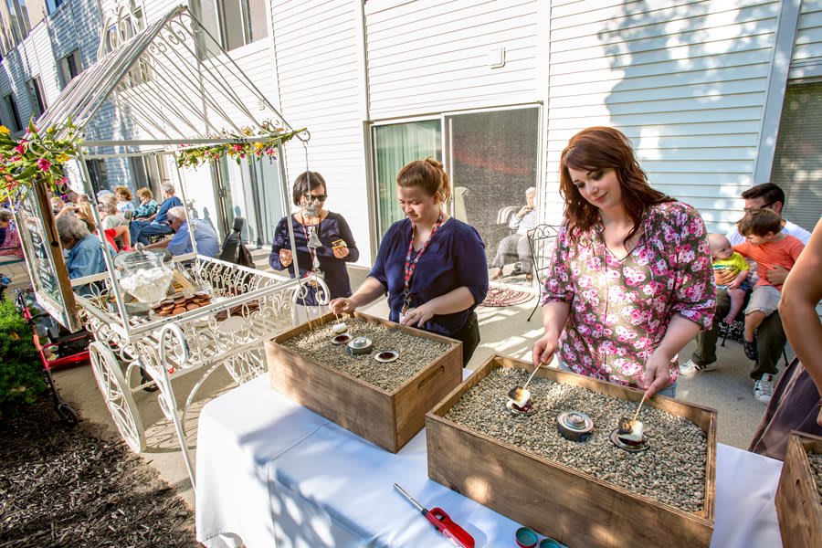 Women participating in an outdoor art activity involving sand trays.