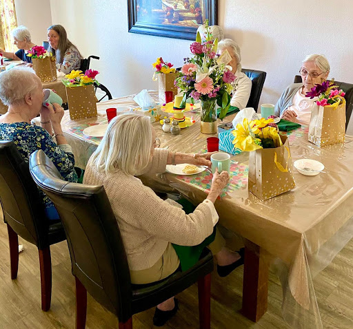 A joyful gathering of seniors surrounded by flowers, enjoying each other's company.