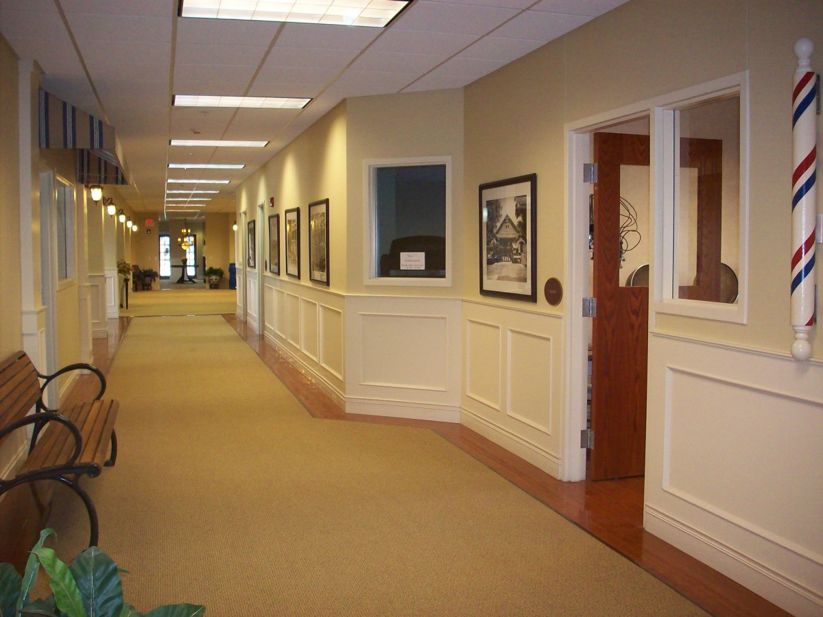 A well-lit office hallway featuring framed artwork and carpeted flooring.