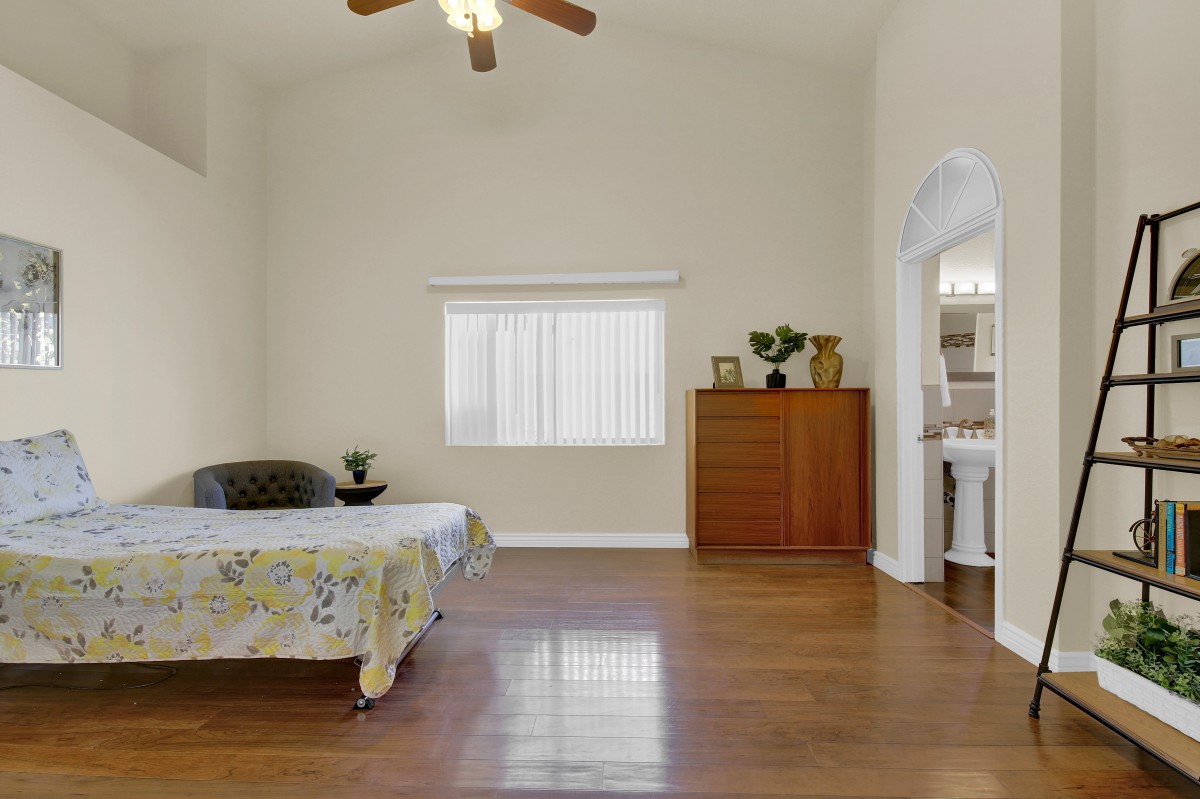 A minimalist bedroom with hardwood flooring and simple furnishings.