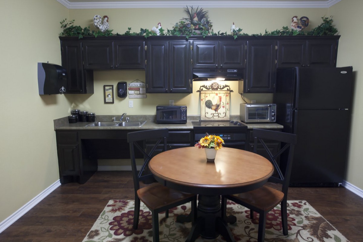 A cozy kitchen setting featuring dark cabinets, a round dining table with chairs, and decorative elements.