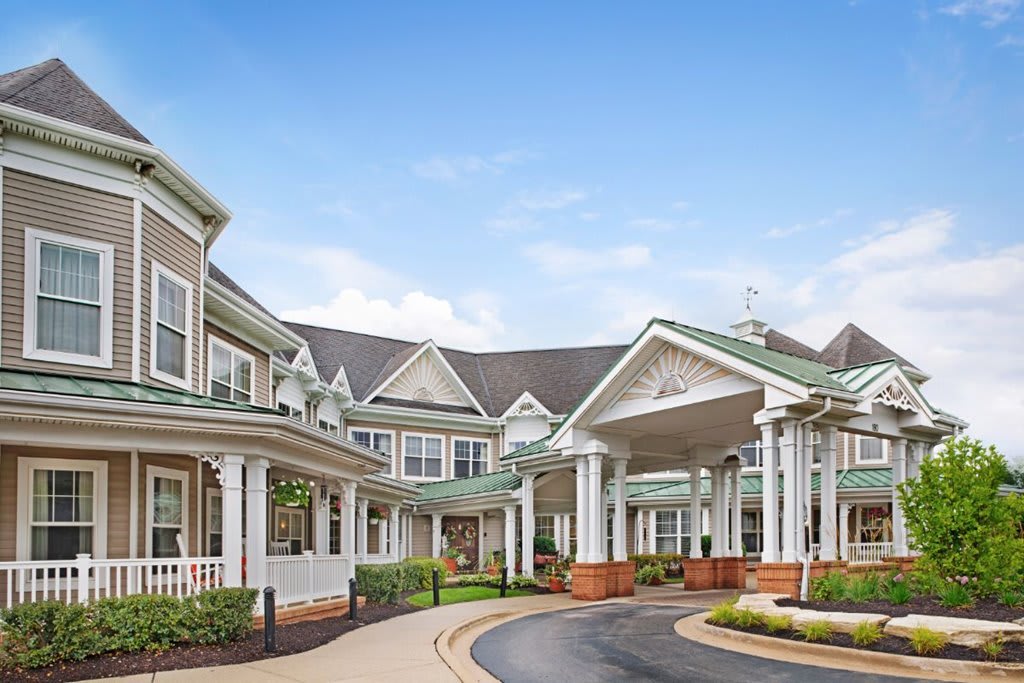A large residential building with a covered entrance and landscaped surroundings.