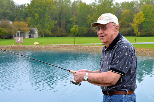A joyful senior man enjoying a peaceful day fishing by the lake.