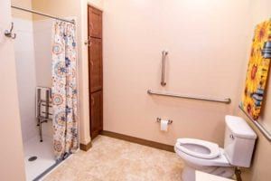 An accessible bathroom with a shower, grab bar, and toilet.