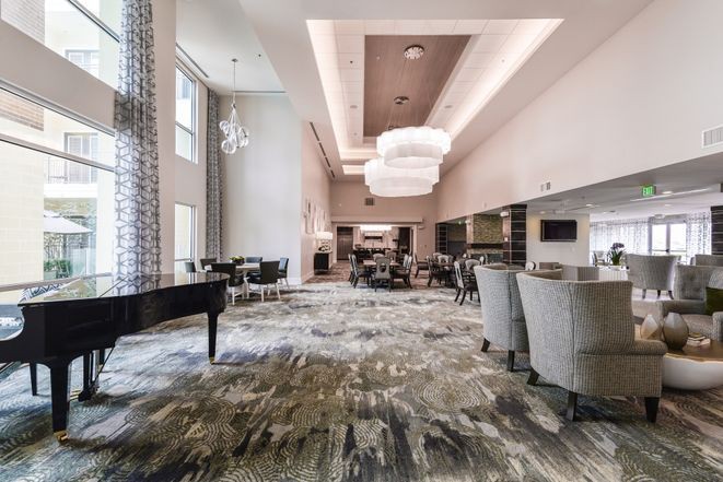 A modern lounge area featuring a grand piano, elegant chandeliers, and comfortable seating.