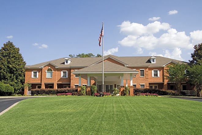 A large building with a manicured lawn and a flag flying at the entrance.