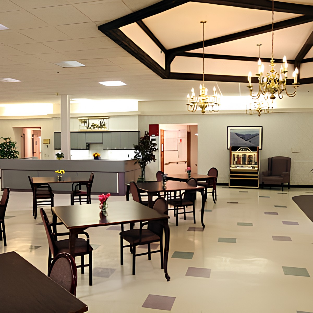 Spacious dining area with tables and chairs under elegant chandeliers.