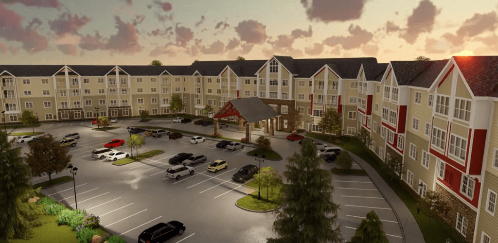 A large residential complex with a spacious parking lot, set against a picturesque sunset.