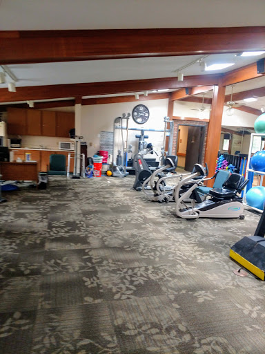 A spacious indoor gym area featuring various exercise machines and fitness equipment.