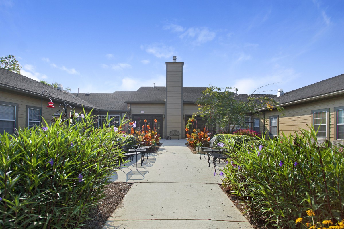 A pathway leading through a landscaped garden to a building entrance under a clear blue sky.