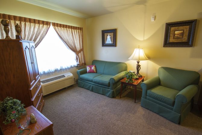 A cozy living room with a green sofa, armchair, and warm lighting.
