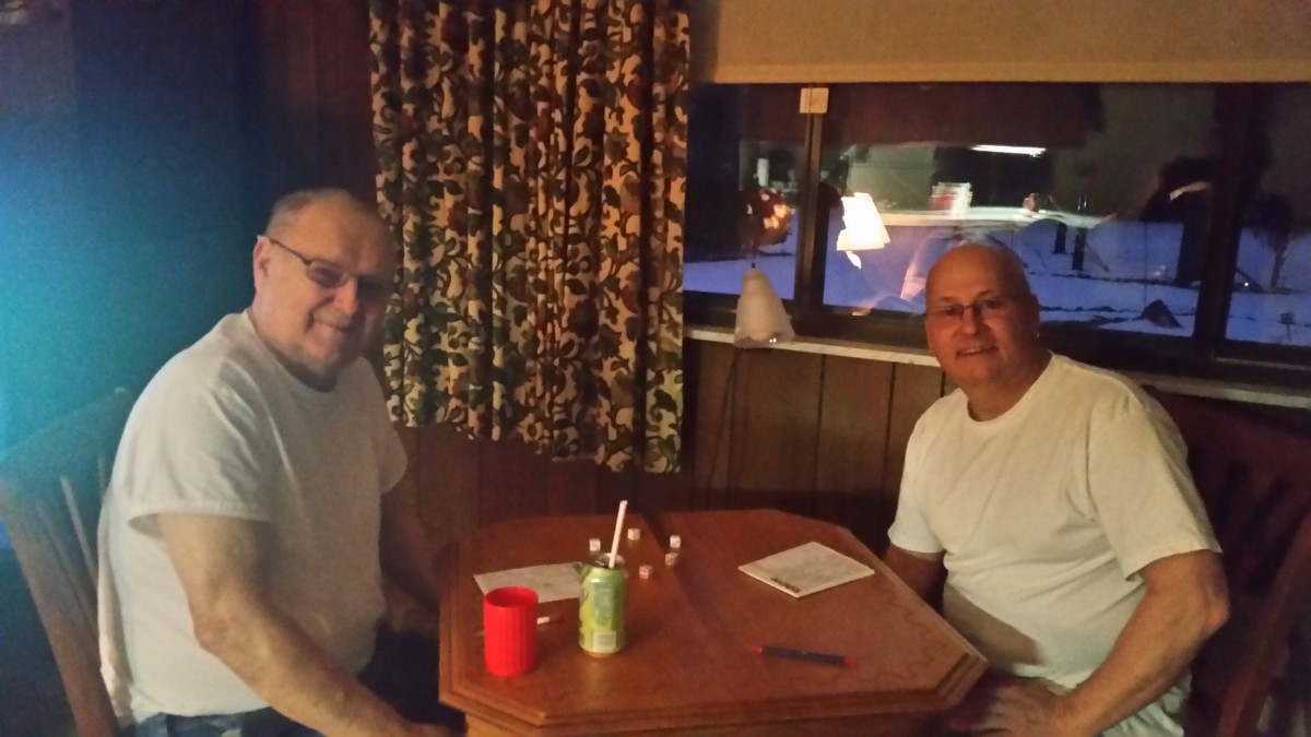 Two individuals sitting at a table with drinks, inside a dimly lit room.
