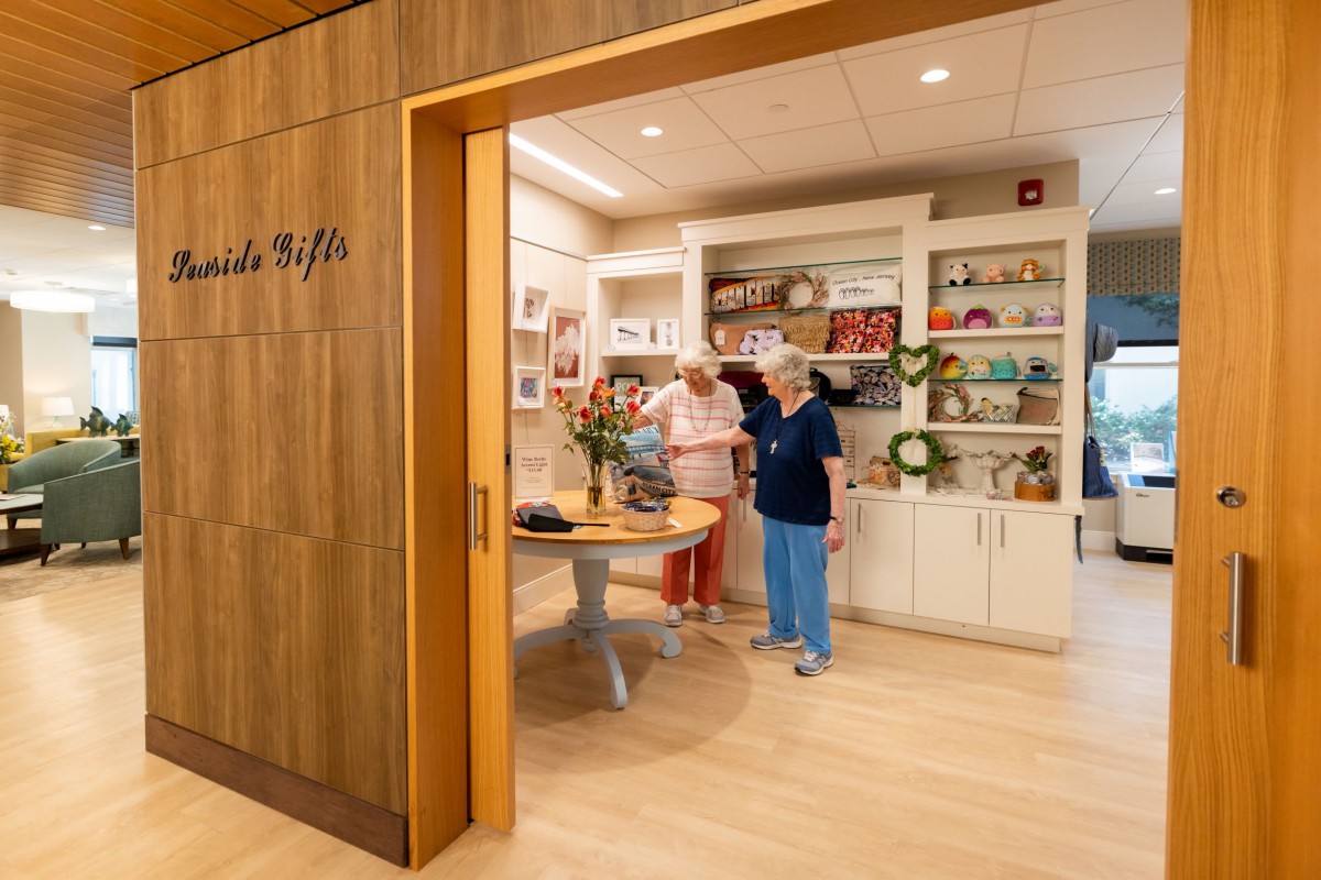 Two people explore a cozy store interior with shelves filled with decorative items.