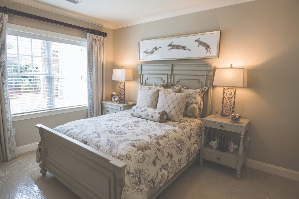 A cozy bedroom with a neatly made bed, featuring floral bedding and two bedside tables with lamps.