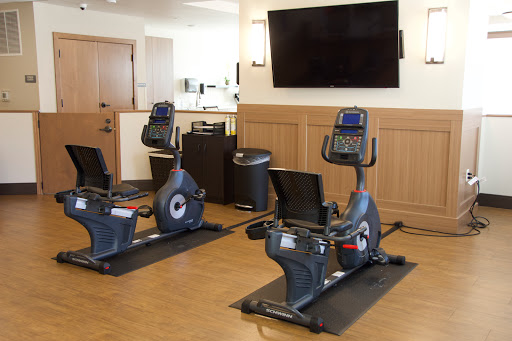 A modern gym area featuring two recumbent exercise bikes and a wall-mounted television.