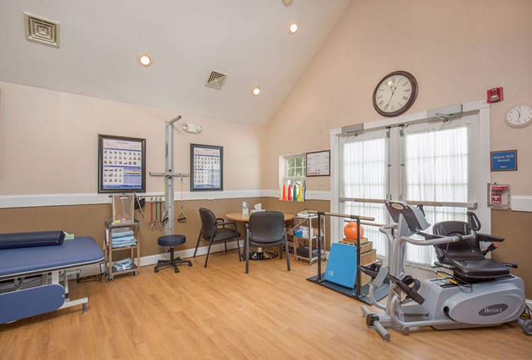 A clean and well-organized exercise room with gym equipment, including a stationary bike, designed for fitness and rehabilitation activities.