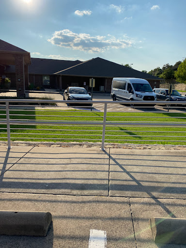 A view of a building with vehicles parked in front on a sunny day.