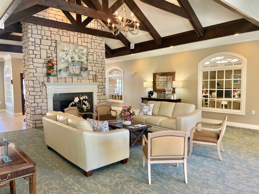 A cozy living room featuring a stone fireplace, elegant furniture, and a beamed ceiling with a chandelier.