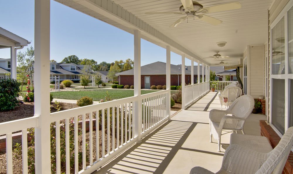 A spacious porch overlooking a community area with chairs and ceiling fans.