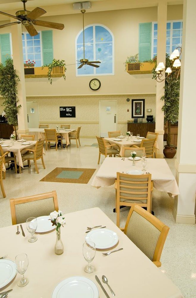 A well-lit dining area with neatly arranged tables and chairs, adorned with plants and decorative elements.