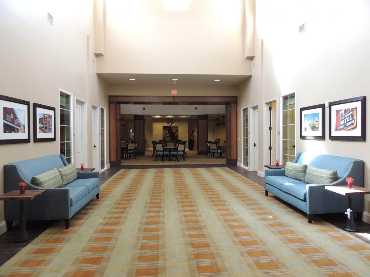 A modern lobby with sofas and a patterned carpet leading to another room.