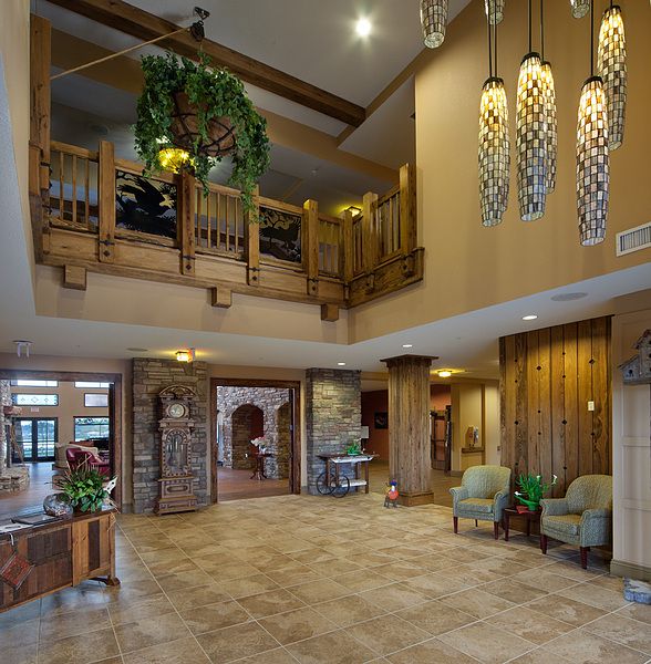 A spacious lobby featuring wooden elements, elegant chandeliers, and comfortable seating areas with lush greenery.
