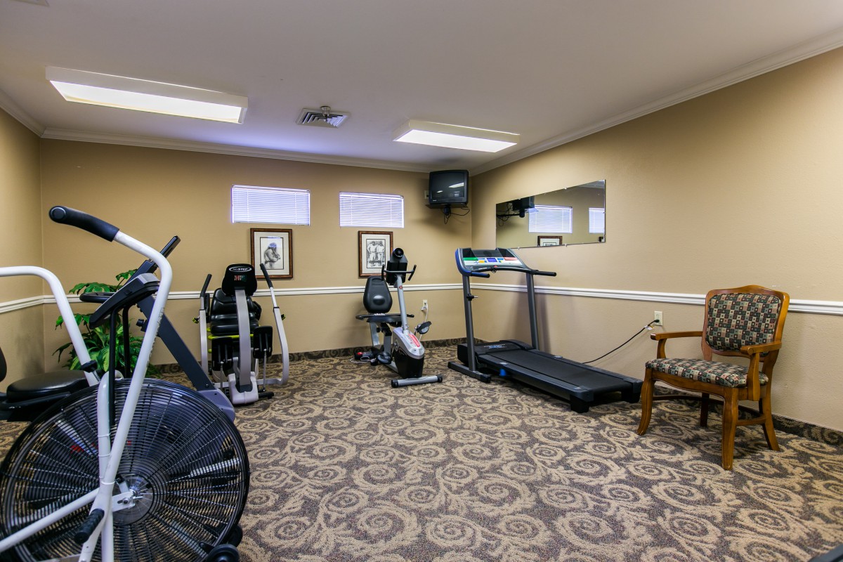 A small fitness room equipped with exercise machines, including a treadmill and stationary bike.
