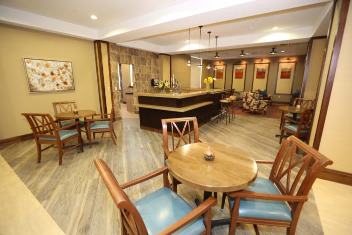 A cozy lounge area with wooden tables and chairs, featuring a reception desk and warm decor.