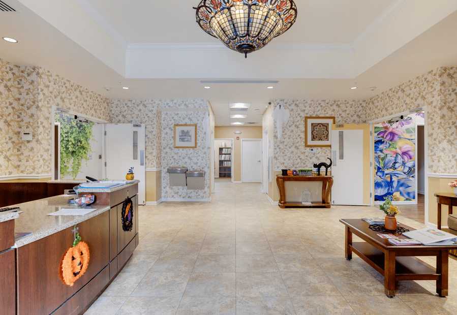 A spacious lobby area with modern decor, featuring a chandelier and reception desk.