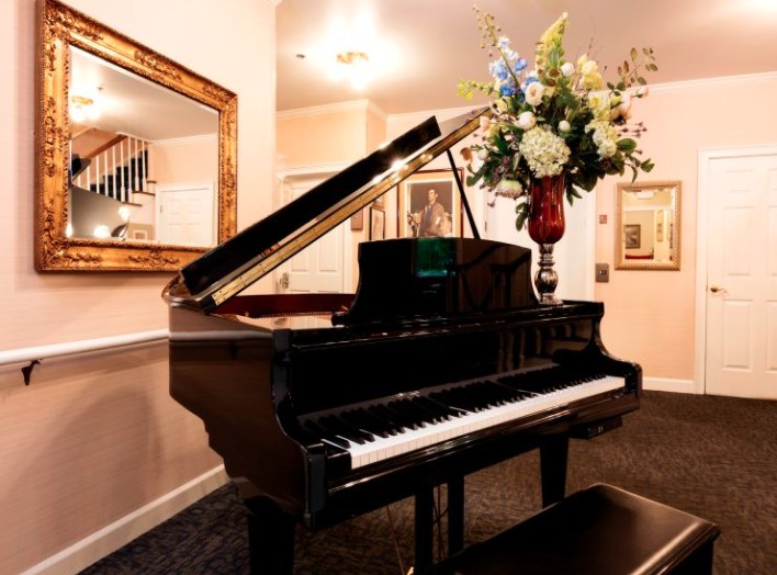 A grand piano elegantly situated in a well-decorated interior with a floral arrangement on top.