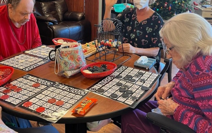 A group of elderly people playing bingo at a table.