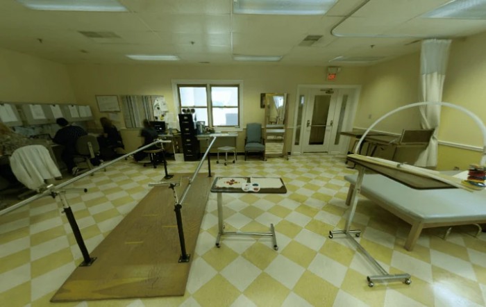 A therapy room equipped with parallel bars and medical equipment for rehabilitation exercises.
