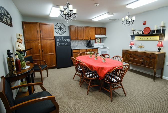 A cozy dining area with a table set for a meal, surrounded by wooden chairs and kitchen cabinets.